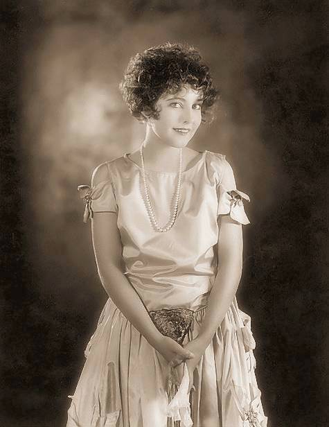 studio-portrait-movie-star-betty-bronson-facing-camera-in-satiny-dress-with-hands-folded