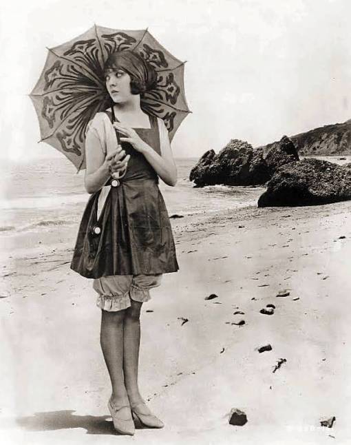 photo-likely-for-arcade-card-movie-star-lila-lee-on-beach-with-parasol-and-long-swim-suit