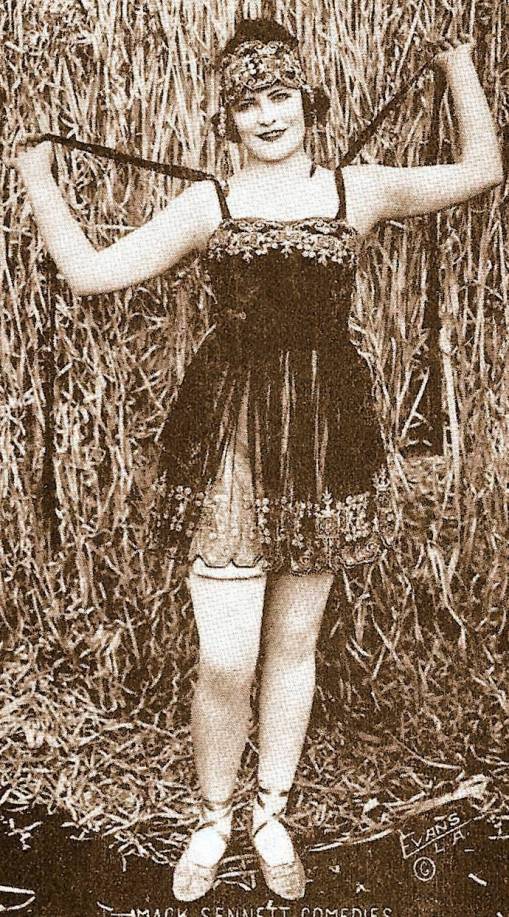 arcade-card-mack-sennett-comedies-woman-in-front-of-straw-with-headband-and-elaborite-short-dress