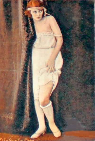 arcade-card-exhibit-supply-company-pin-up-woman-in-nightie-and-headband-by-curtain-lifting-the-hem-on-one-leg-tinted-1920s