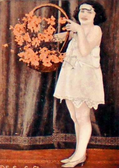 arcade-card-exhibit-supply-company-pin-up-woman-in-nightie-with-headband-holding-basket-of-flowers-tinted-1920s