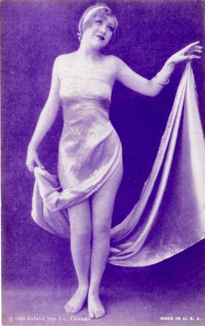 arcade-card-exhibit-supply-company-pin-up-woman-in-long-satainy-dress-holding-long-train-and-headband-1929