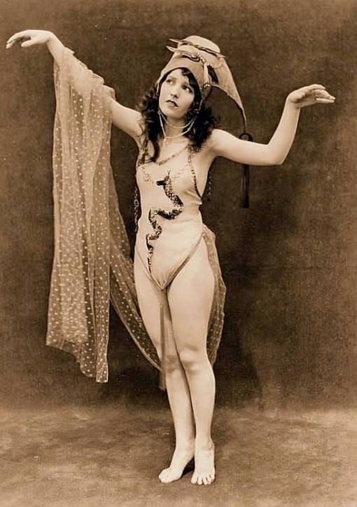 photo-for-arcade-card-exhibit-supply-company-woman-standing-in-dance-pose-with-exotic-hat-and-dotted-veil-1920s