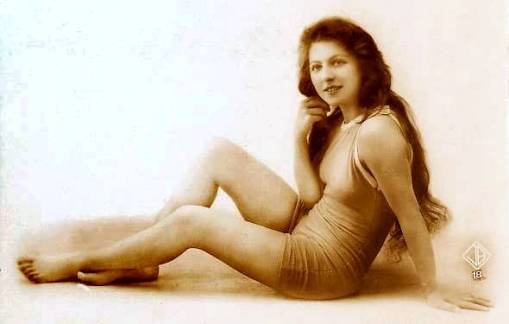 arcade-card-french-woman-in-bathing-suit-with-long-hair-sitting-leaning-on-one-arm-1920s
