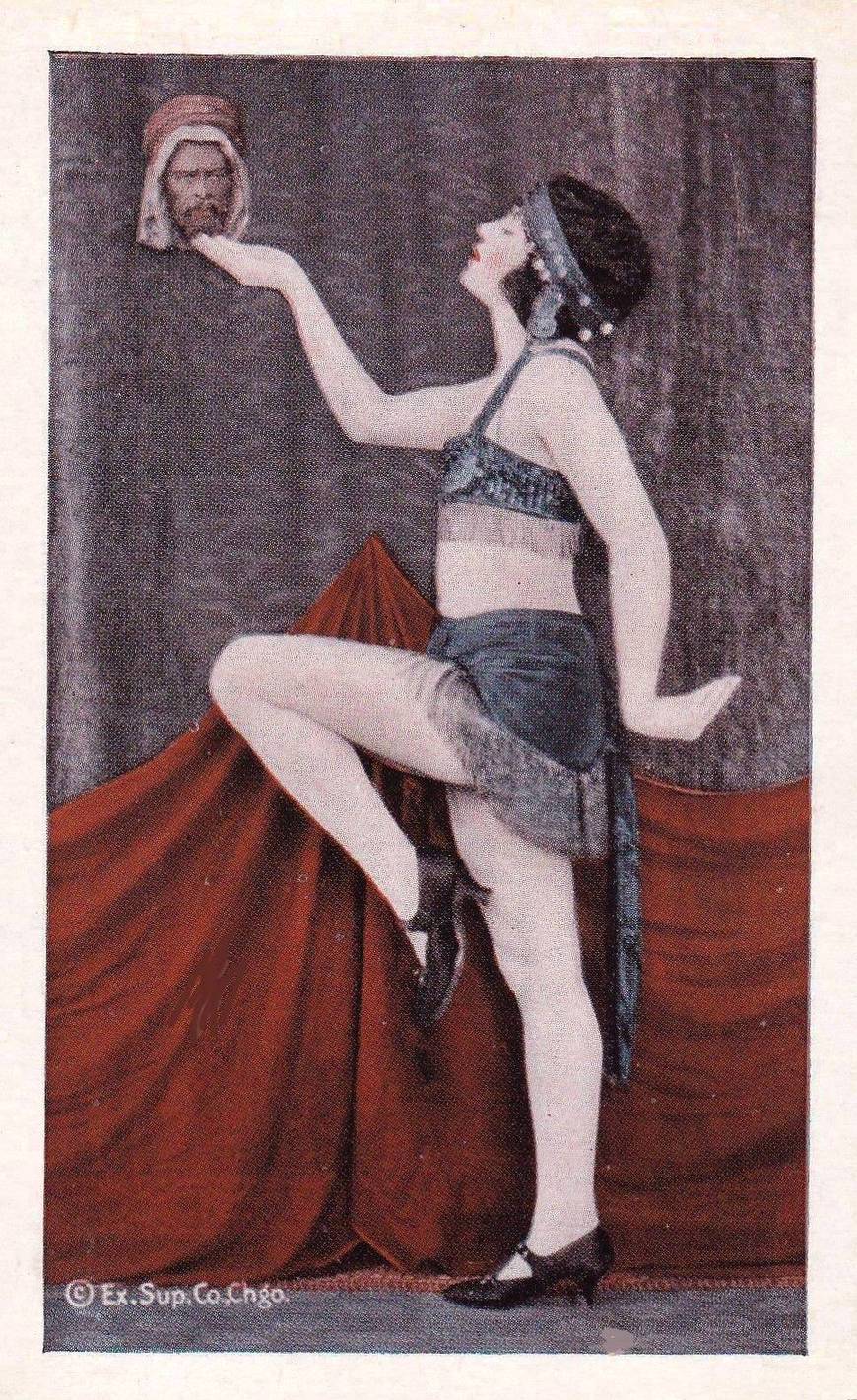 A ARCADE CARD - EXHIBIT SUPPLY COMPANY - WOMAN MARCHING PROFILE HOLDING UP A SMALL HEAD IN ONE HAND - TINTED SERIES - 1920s
