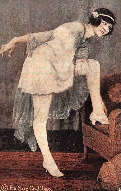 ARCADE CARD - EXHIBIT SUPPY COMPANY- PIN-UP - WOMAN IN CROPPED HAIR AND HEADBAND IN NIGHTIE WITH FOOT ON WICKER CHAIR LEANS OVER TO ADJUST SHOE WHILE LOOKING TOWARDS CAMERA - GRACEFUL FL