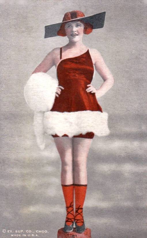 ARCADE CARD - EXHIBIT SUPPLY COMPANY - PHYLLIS HAVER IN RED AND WHITE CHRISTMASY OUTFIT WITH OUTLANDISH SUN HAT STANDING ON POST WITH HANDS ON HIPS - TINTED - 1920s