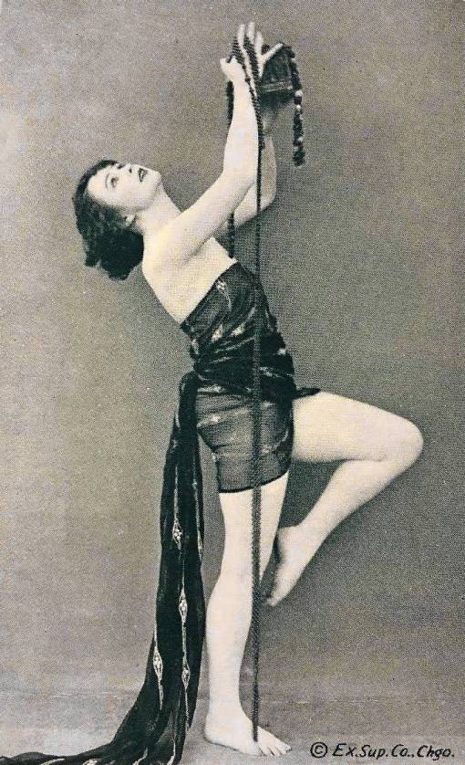 ARCADE CARD - EXHIBIT SUPPLY COMPANY - WOMAN IN SILKY WRAP HEAD BACK HANDS UP WITH BEADS IN DANCE POSE - 1920s